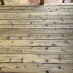 Close-up view of a weathered wooden deck surface showing various imperfections, highlighting the need for restoration and maintenance, relevant to deck cleaning and staining discussions.
