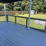 Newly stained deck with solid Coastal Gray finish, showcasing clean lines and a spacious layout, surrounded by greenery and a shed in the background, illustrating a successful wood restoration project.
