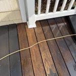 IPE hardwood deck with contrasting stained sections and a power washing hose, illustrating the effects of deck maintenance and staining options.