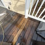 Deck surface showing various shades of stained hardwood with power washing equipment, highlighting cleaning process for IPE wood.